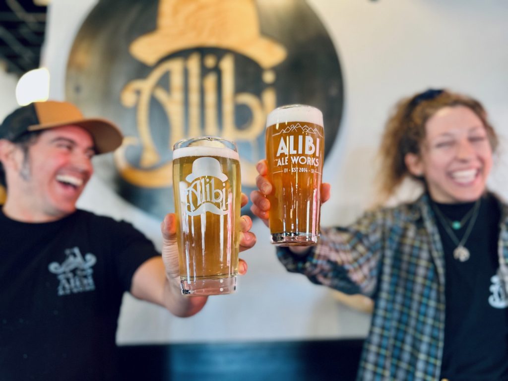 Friends raising Alibi Ale Works beers in the taproom